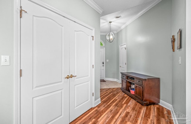 corridor featuring crown molding, a textured ceiling, and hardwood / wood-style flooring