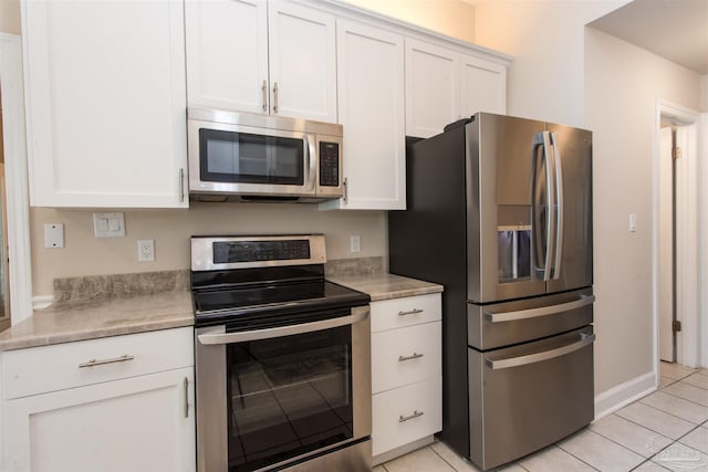 kitchen with light tile patterned flooring, white cabinets, and appliances with stainless steel finishes