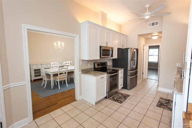 kitchen with appliances with stainless steel finishes, light tile patterned floors, and white cabinets