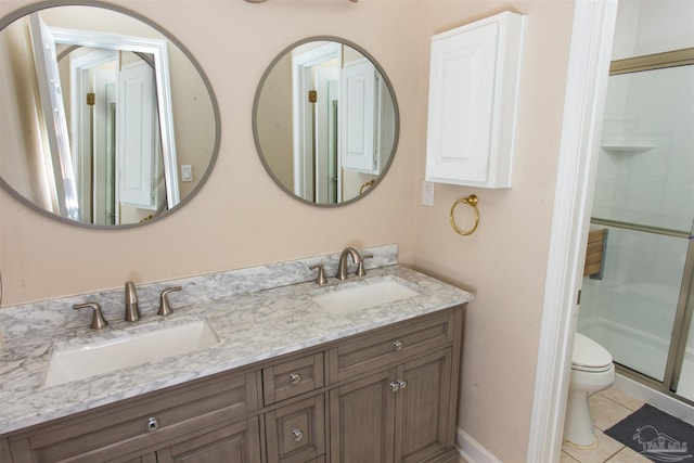 bathroom with a shower with door, vanity, tile patterned floors, and toilet