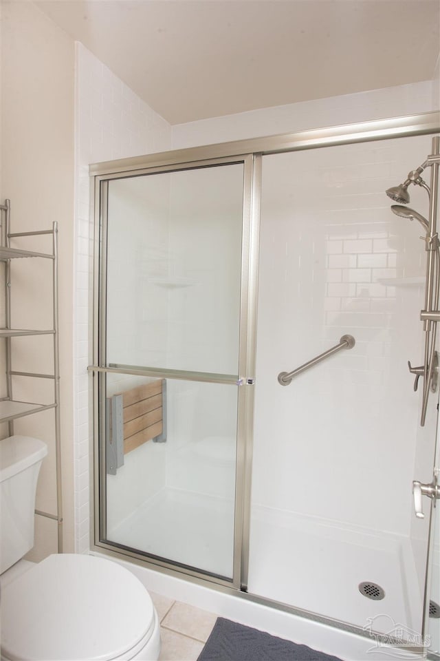 bathroom with tile patterned floors, toilet, and a shower with shower door