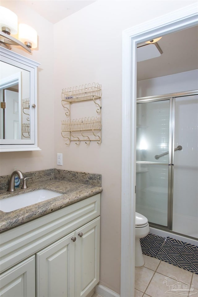 bathroom featuring vanity, toilet, a shower with shower door, and tile patterned flooring