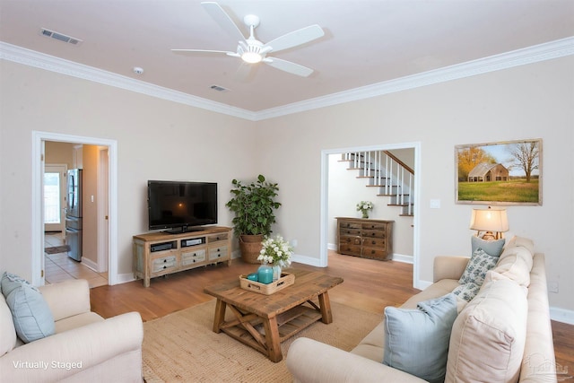 living room featuring ceiling fan, ornamental molding, and light hardwood / wood-style floors