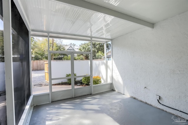 unfurnished sunroom featuring beam ceiling