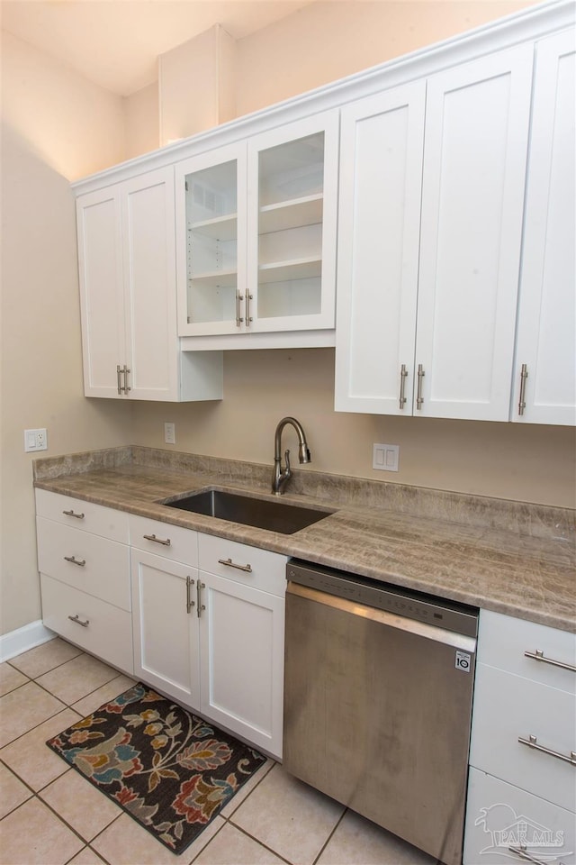 kitchen featuring white cabinetry, dishwasher, sink, light tile patterned floors, and light stone countertops