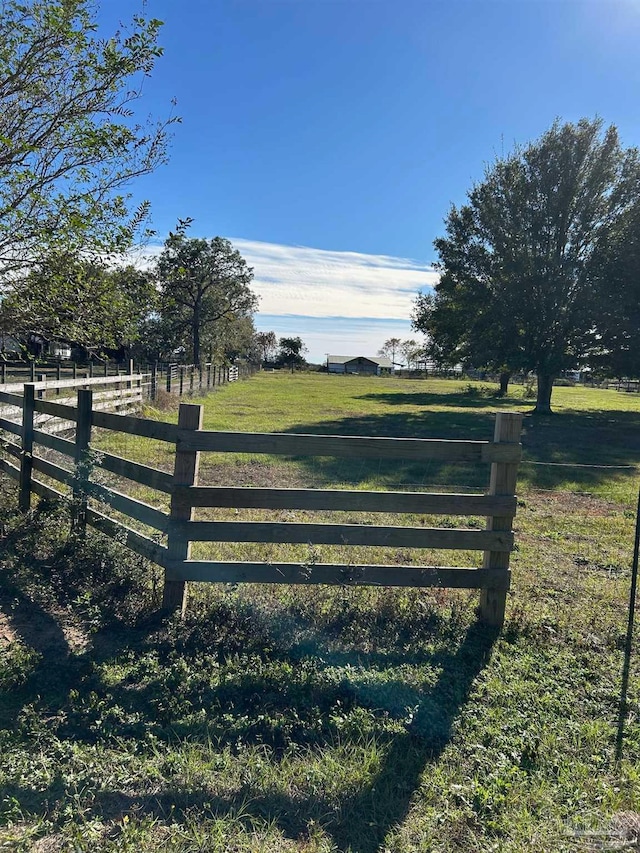 view of gate with a yard and a rural view