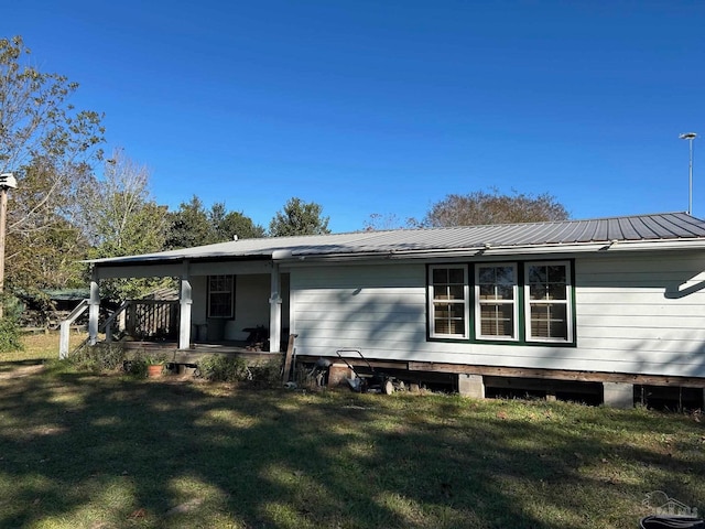 rear view of property featuring a yard and covered porch