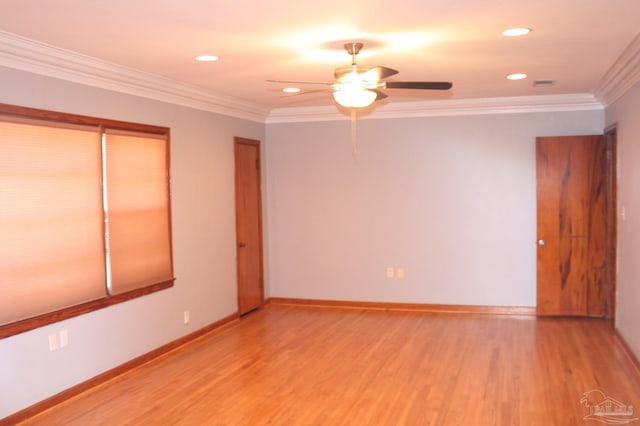 empty room with ornamental molding, light wood-style flooring, and baseboards