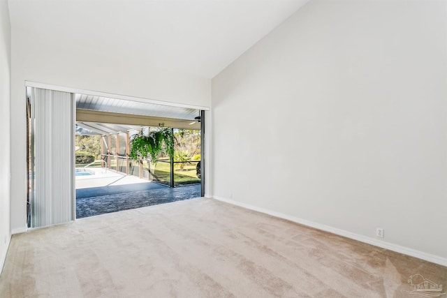 carpeted spare room with baseboards, lofted ceiling, and a sunroom