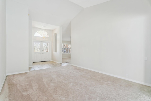 carpeted entryway featuring baseboards, a notable chandelier, high vaulted ceiling, and tile patterned flooring