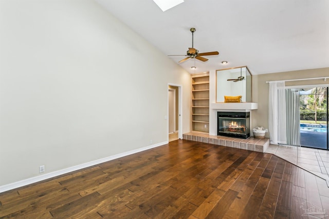 unfurnished living room featuring a tiled fireplace, hardwood / wood-style floors, baseboards, ceiling fan, and vaulted ceiling