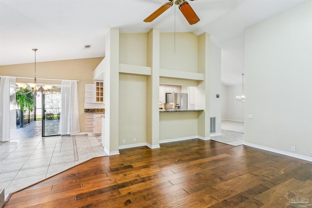 unfurnished living room featuring visible vents, ceiling fan with notable chandelier, baseboards, and hardwood / wood-style flooring