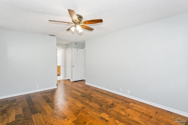 spare room with visible vents, a ceiling fan, a textured ceiling, baseboards, and dark wood-style flooring