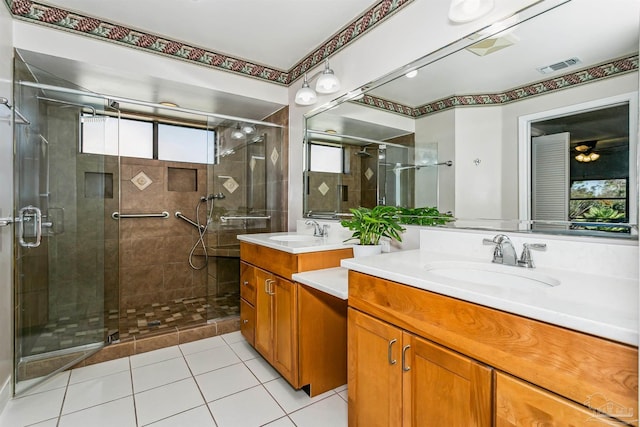 bathroom featuring visible vents, a stall shower, two vanities, and a sink