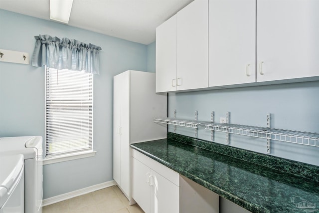 laundry area featuring light tile patterned floors, baseboards, cabinet space, and washing machine and clothes dryer