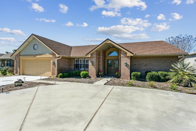 view of front of property featuring brick siding, an attached garage, concrete driveway, and roof with shingles