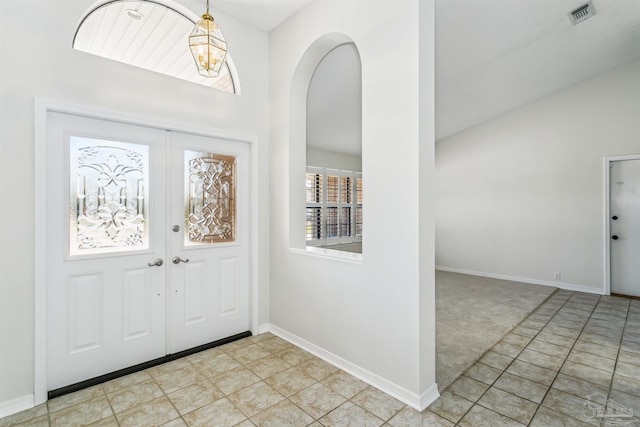 foyer featuring baseboards, visible vents, arched walkways, vaulted ceiling, and french doors