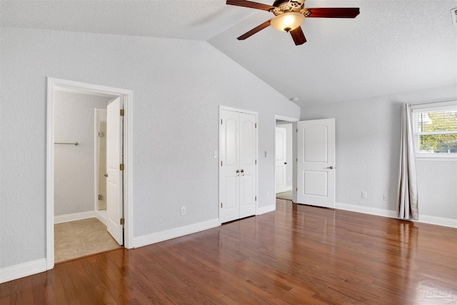 unfurnished bedroom with ensuite bathroom, lofted ceiling, dark hardwood / wood-style floors, and ceiling fan