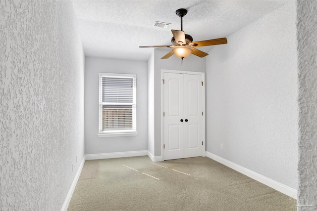 carpeted empty room featuring ceiling fan and a textured ceiling