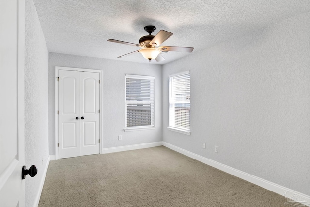 carpeted spare room with ceiling fan and a textured ceiling