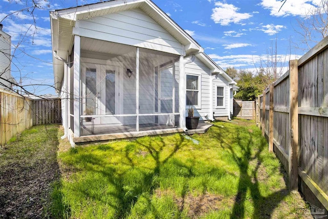 back of house featuring a sunroom and a lawn