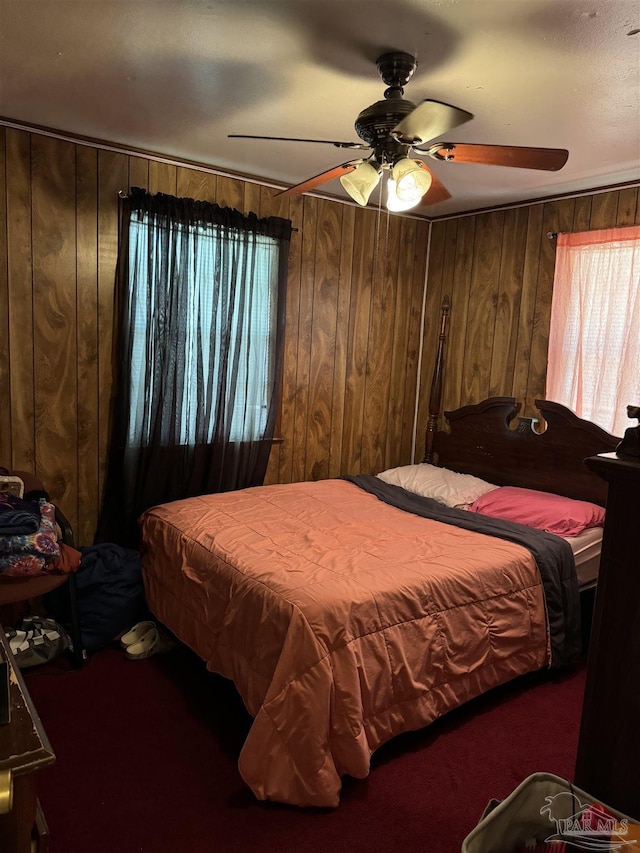 bedroom featuring ceiling fan, carpet floors, and wood walls