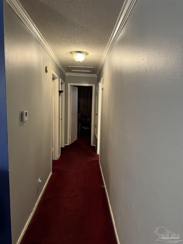 corridor with a textured ceiling, crown molding, and carpet