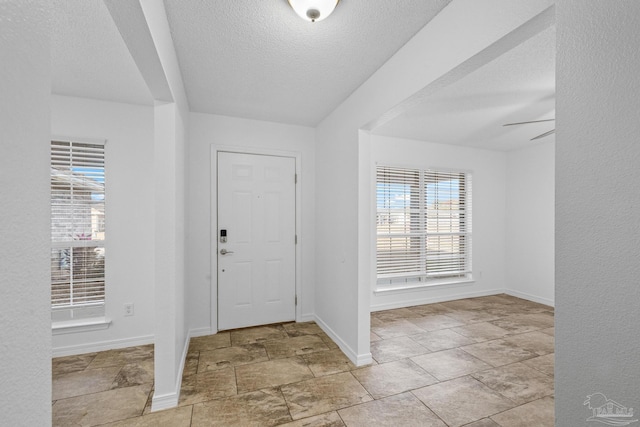 foyer entrance featuring ceiling fan and a textured ceiling