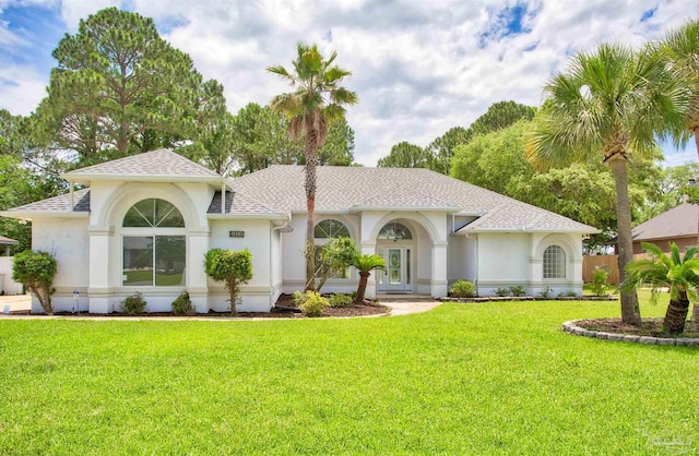 view of front of property with stucco siding, a front yard, and a shingled roof