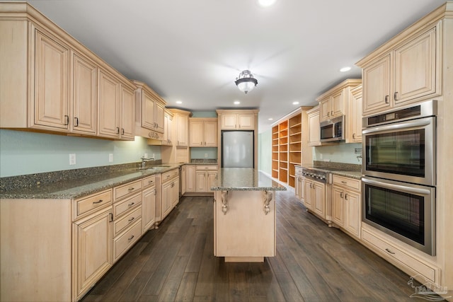 kitchen featuring a kitchen bar, appliances with stainless steel finishes, sink, a kitchen island, and dark wood-type flooring