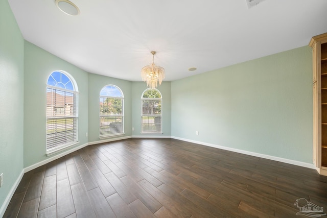 empty room with dark hardwood / wood-style flooring and a notable chandelier