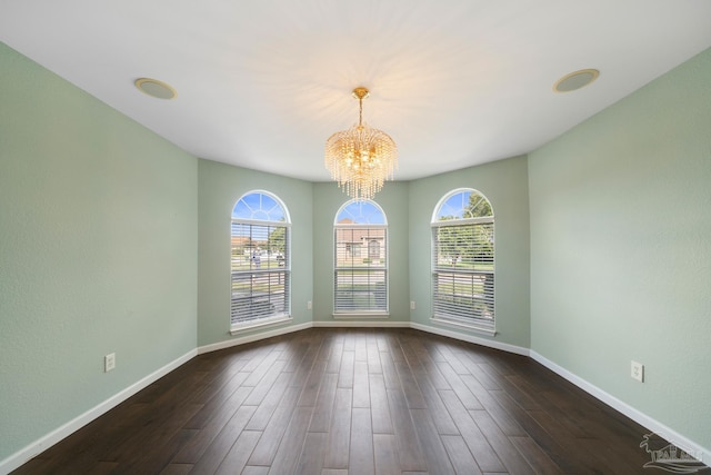 empty room featuring dark hardwood / wood-style flooring and an inviting chandelier