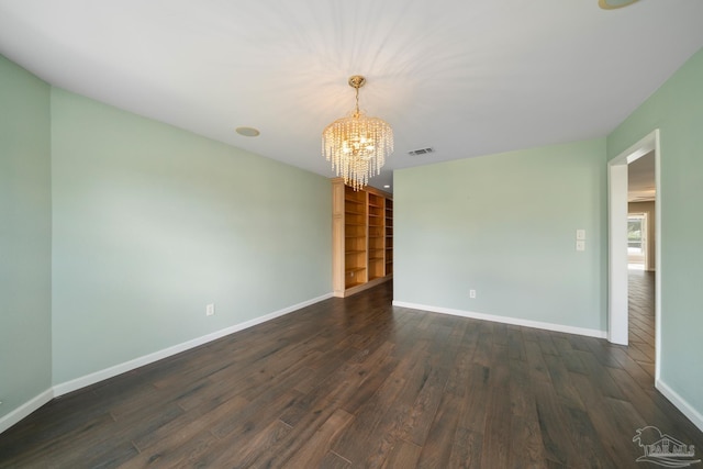 unfurnished room featuring an inviting chandelier and dark hardwood / wood-style floors