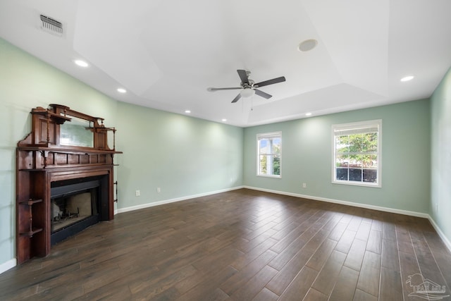 unfurnished living room with ceiling fan, dark hardwood / wood-style floors, and a raised ceiling