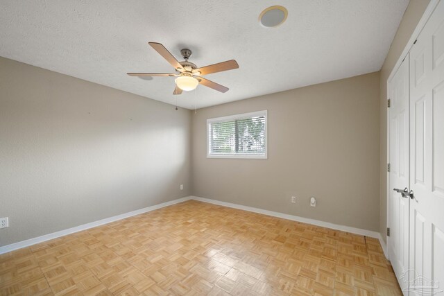 spare room with ceiling fan, light parquet flooring, and a textured ceiling