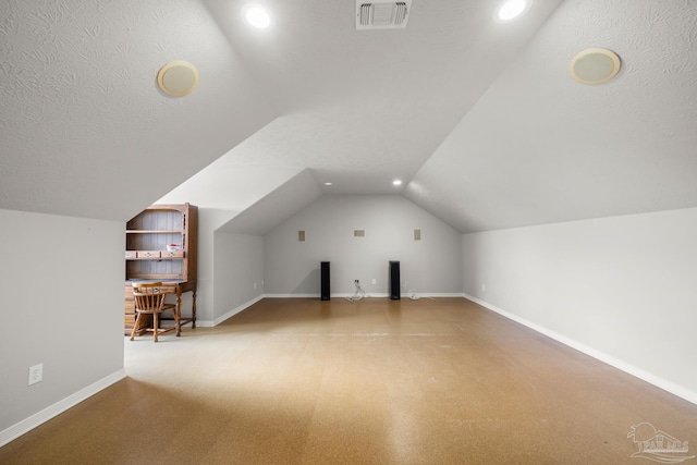 bonus room featuring a textured ceiling, vaulted ceiling, and light colored carpet