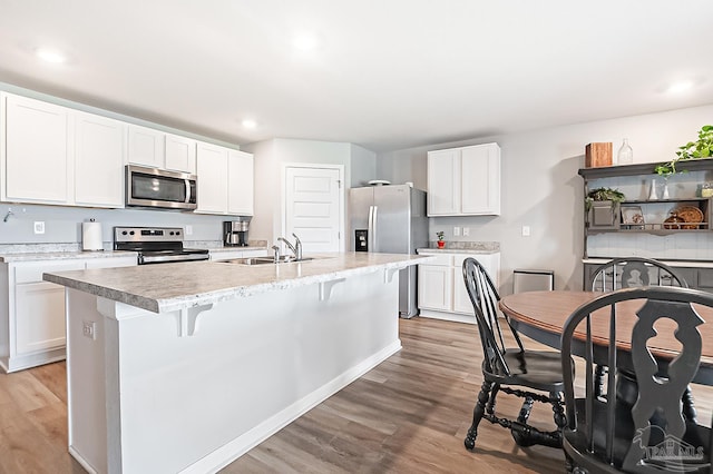 4366 White Cedar Ct, Pace, FL 32571 - kitchen featuring appliances with stainless steel finishes, a sink, light wood-style flooring, light countertops, and a kitchen island with sink