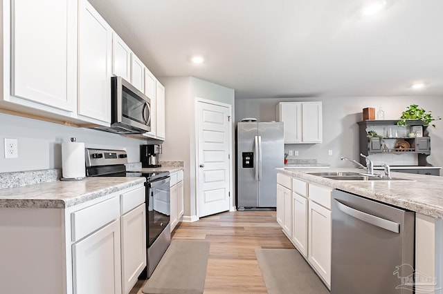 4366 White Cedar Ct, Pace, FL 32571 - kitchen with appliances with stainless steel finishes, a sink, light wood-style floors, white cabinets, and light countertops