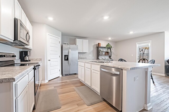 4366 White Cedar Ct, Pace, FL 32571 - kitchen with stainless steel appliances, a sink, light wood-style floors, white cabinetry, and recessed lighting