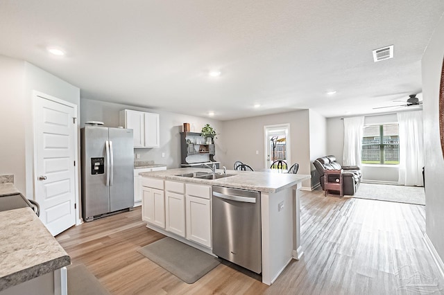 4366 White Cedar Ct, Pace, FL 32571 - kitchen with stainless steel appliances, a sink, light wood-style floors, white cabinets, and a kitchen island with sink