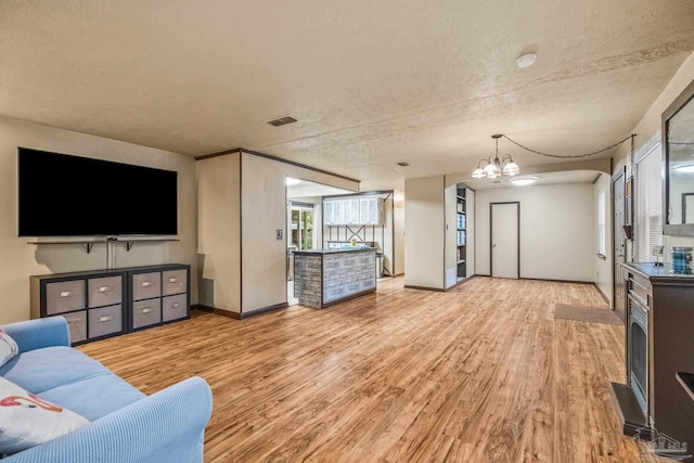 living room featuring light hardwood / wood-style flooring, a textured ceiling, and an inviting chandelier