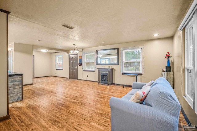 living room featuring a fireplace, a textured ceiling, and light wood-type flooring