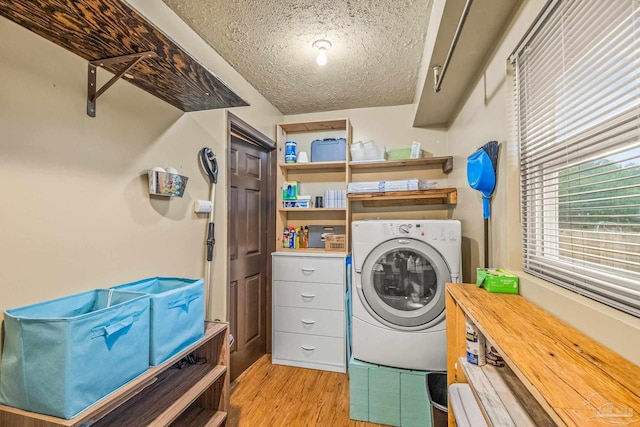 clothes washing area featuring light hardwood / wood-style flooring, a textured ceiling, and washer / dryer