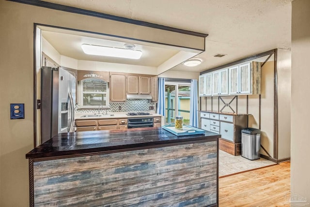 kitchen with light brown cabinetry, light wood-type flooring, backsplash, stainless steel appliances, and sink