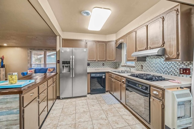 kitchen featuring decorative backsplash, heating unit, sink, black appliances, and light tile patterned floors