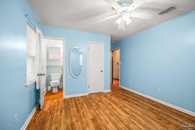 unfurnished bedroom featuring ensuite bath, ceiling fan, and hardwood / wood-style flooring