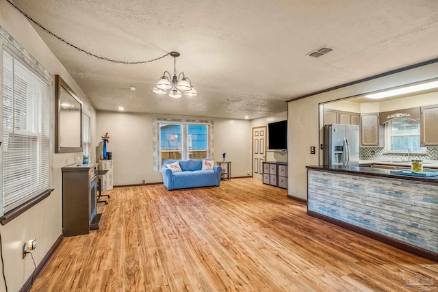 living room featuring a chandelier, a textured ceiling, light hardwood / wood-style floors, and a wealth of natural light