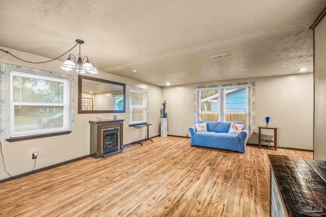 living room featuring a notable chandelier, light hardwood / wood-style floors, and a textured ceiling