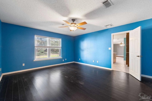 empty room with visible vents, wood finished floors, and ceiling fan