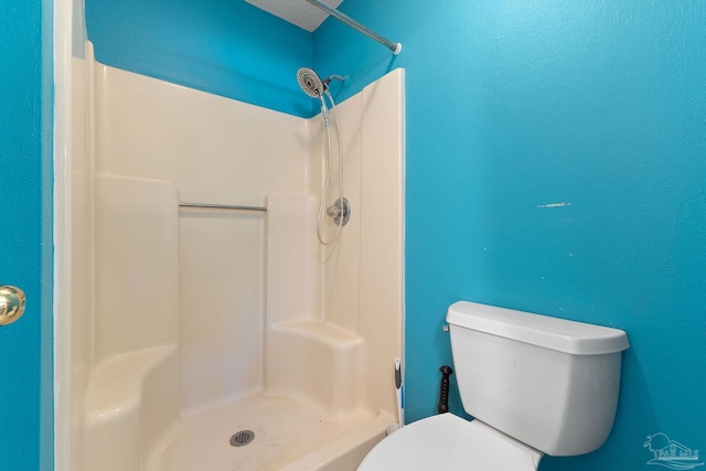 bathroom with a shower stall and toilet